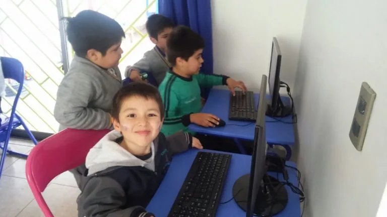 Niños usando la sala de computadores de Happy Time